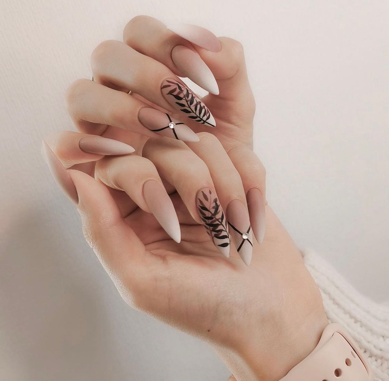 Hands showing fine-line black nail art on a light base