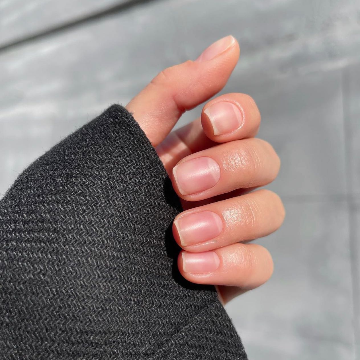 Hand with short, glossy rose-coloured nails