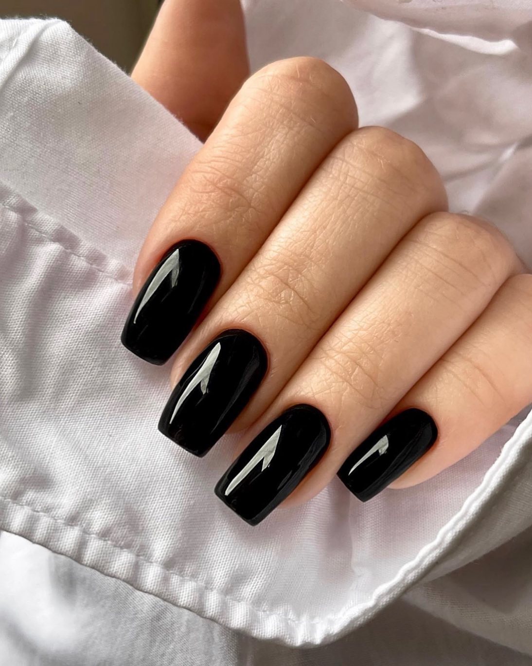 Glossy black manicure with geometric white accents