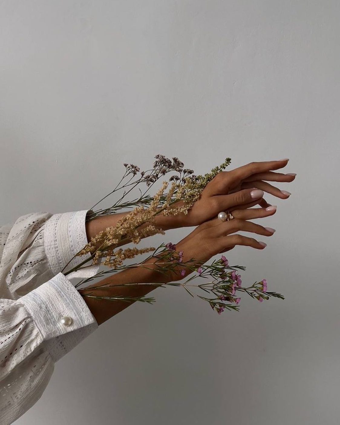 Hands with nude nails holding dried flowers